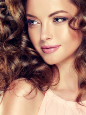Beautiful model girl with wavy hairstyle . Brunette woman with long curly hair